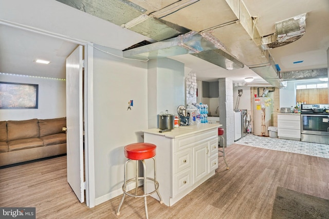 kitchen with stainless steel range with electric stovetop, white cabinets, light hardwood / wood-style floors, and gas water heater