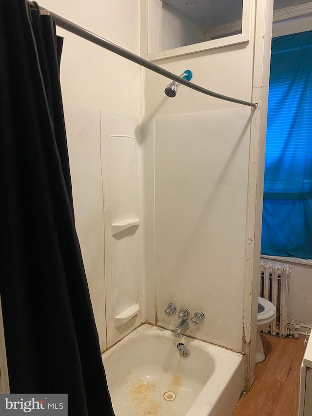 bathroom featuring hardwood / wood-style flooring, toilet, radiator heating unit, and shower / washtub combination