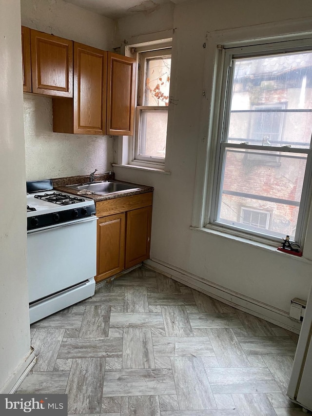 kitchen featuring sink, white stove, a wealth of natural light, and light parquet floors