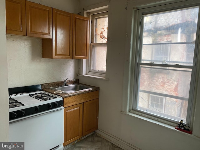 kitchen featuring a healthy amount of sunlight, sink, and white range with gas cooktop