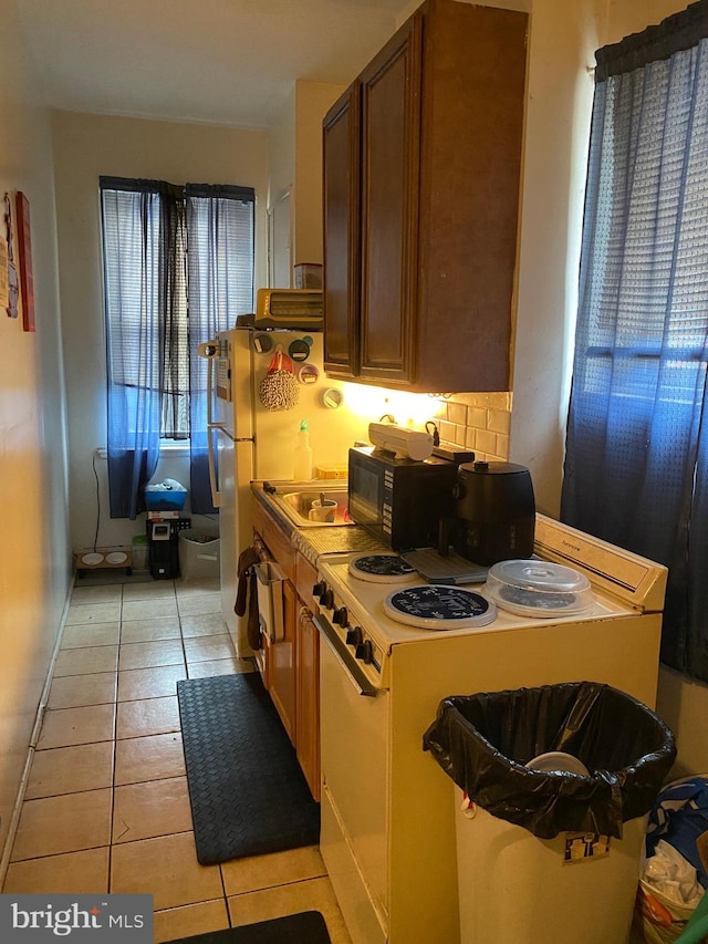 kitchen with white electric range, backsplash, and light tile patterned flooring