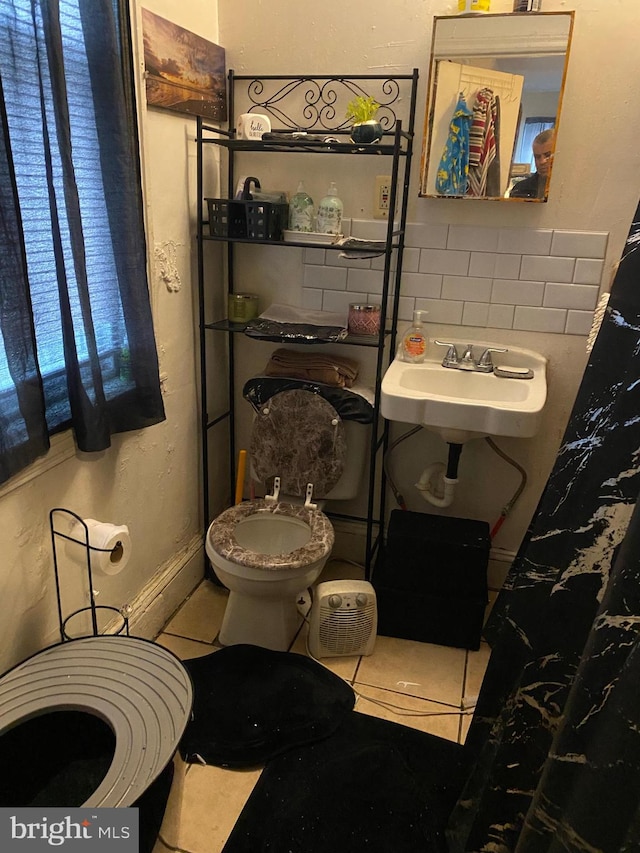 bathroom featuring tile patterned floors, tasteful backsplash, sink, and toilet