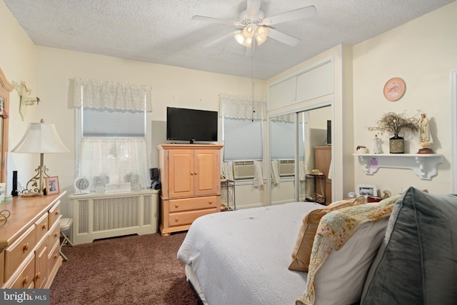 bedroom with ceiling fan, a textured ceiling, radiator, dark carpet, and a closet