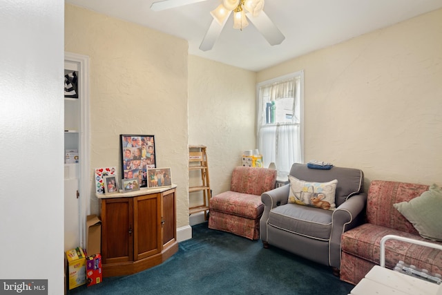 living area with dark carpet and ceiling fan