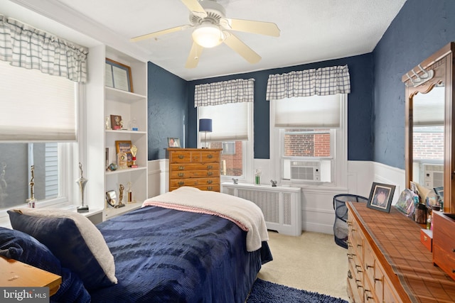 bedroom with cooling unit, radiator heating unit, carpet, and ceiling fan