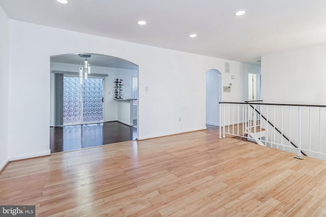 spare room with a wealth of natural light, light hardwood / wood-style flooring, and a chandelier