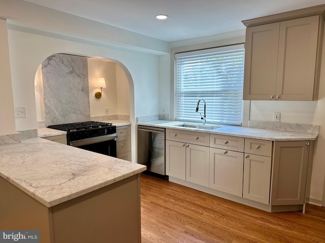 kitchen featuring black gas range, sink, light hardwood / wood-style flooring, stainless steel dishwasher, and kitchen peninsula