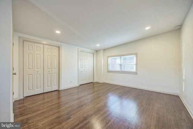 unfurnished bedroom with dark wood-type flooring and two closets