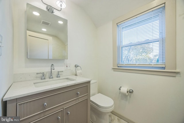 bathroom with vanity, toilet, and lofted ceiling