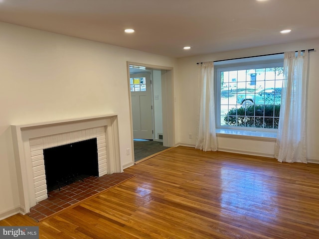 unfurnished living room with dark hardwood / wood-style floors and a brick fireplace