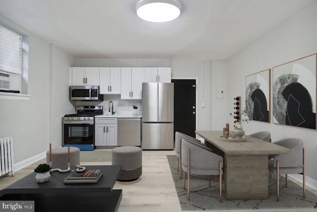 kitchen featuring white cabinets, stainless steel appliances, sink, and light wood-type flooring