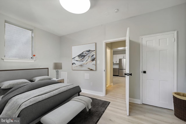 bedroom featuring stainless steel refrigerator and light wood-type flooring