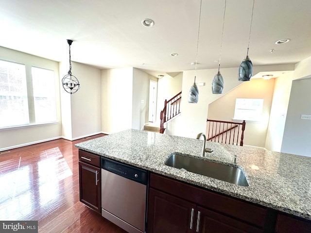 kitchen featuring light stone countertops, sink, dishwasher, wood-type flooring, and pendant lighting