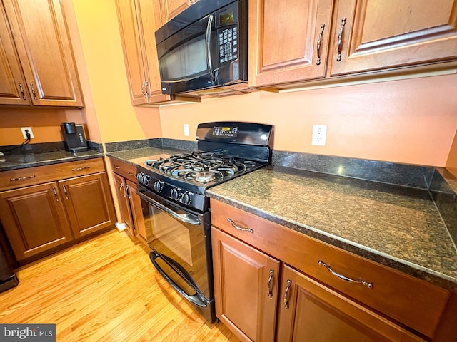 kitchen with light hardwood / wood-style floors and black appliances