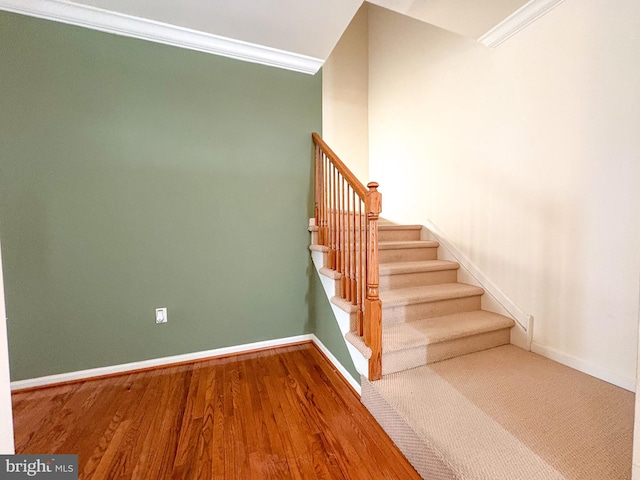 stairs with ornamental molding and hardwood / wood-style flooring