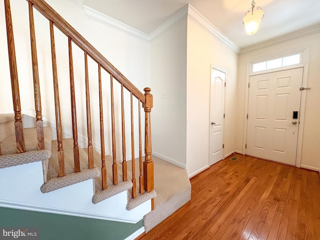 foyer entrance with ornamental molding and hardwood / wood-style flooring