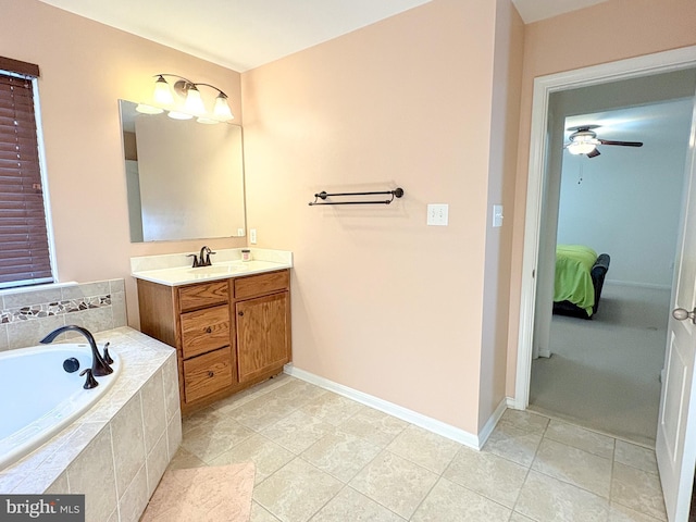 bathroom with tiled tub, ceiling fan, tile patterned flooring, and vanity