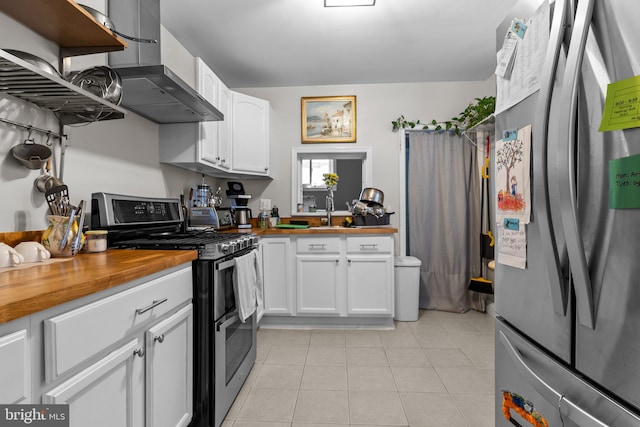 kitchen featuring wall chimney range hood, light tile patterned flooring, sink, white cabinetry, and stainless steel appliances