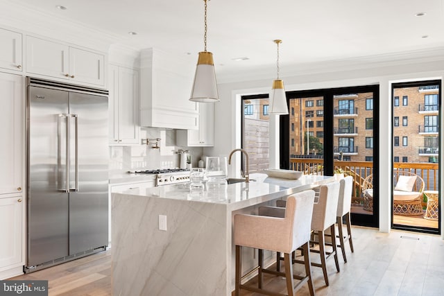 kitchen with light stone countertops, white cabinetry, and stainless steel built in fridge