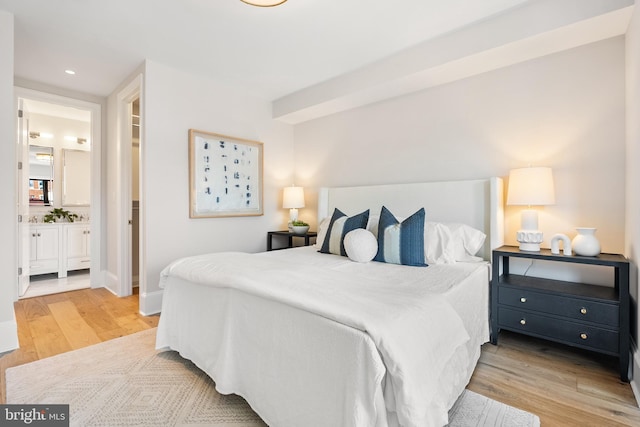 bedroom featuring light wood-type flooring and ensuite bath