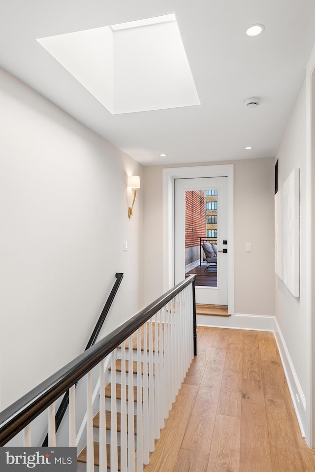 corridor featuring light hardwood / wood-style floors and a skylight