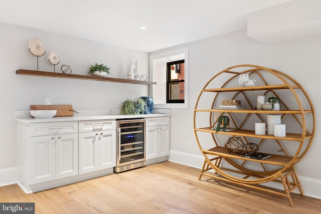 bar featuring wine cooler, white cabinetry, and light hardwood / wood-style floors