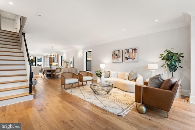 living room featuring a notable chandelier, light wood-type flooring, and ornamental molding