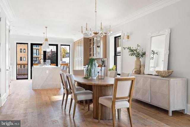 dining area featuring an inviting chandelier, light hardwood / wood-style flooring, crown molding, and sink