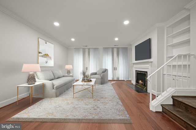 living room featuring ornamental molding, built in shelves, and hardwood / wood-style floors