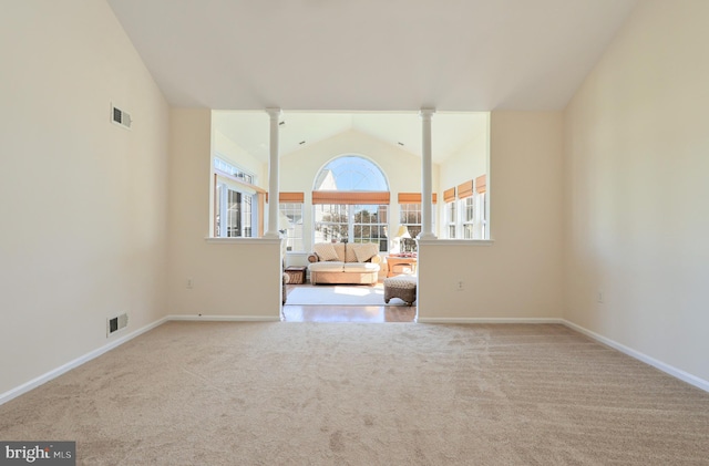 carpeted spare room featuring lofted ceiling and decorative columns