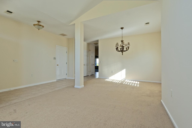 empty room featuring light carpet, an inviting chandelier, and vaulted ceiling