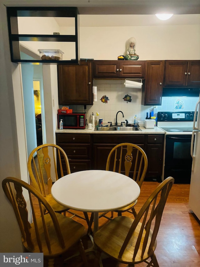 kitchen with white electric range oven, sink, decorative backsplash, and dark brown cabinets