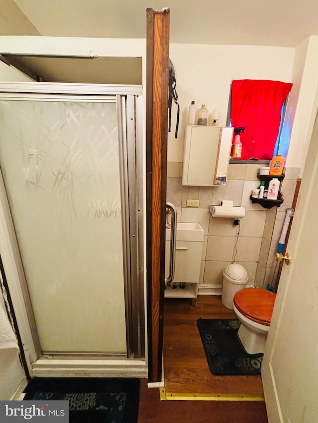 bathroom with toilet, tile walls, an enclosed shower, and hardwood / wood-style floors