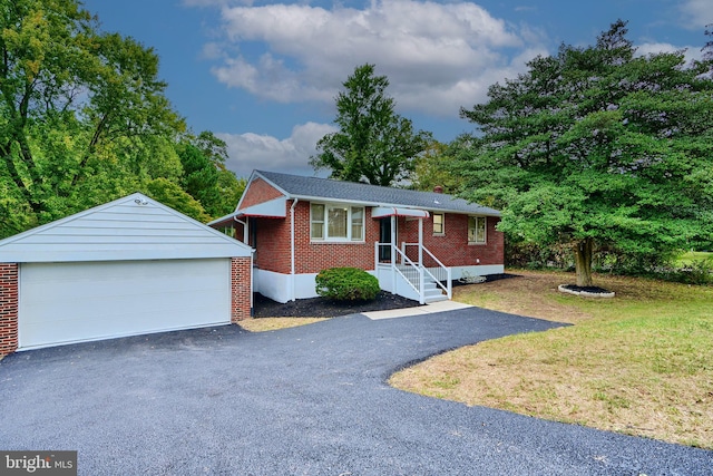 view of front of home featuring a garage, a front lawn, and an outbuilding