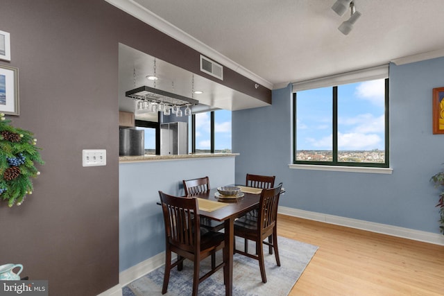 dining area featuring ornamental molding, wood finished floors, and baseboards