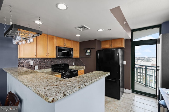 kitchen with black appliances, tasteful backsplash, a peninsula, light tile patterned flooring, and light stone countertops