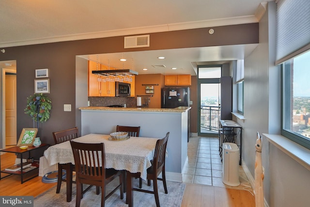 dining room featuring light hardwood / wood-style flooring, ornamental molding, and plenty of natural light