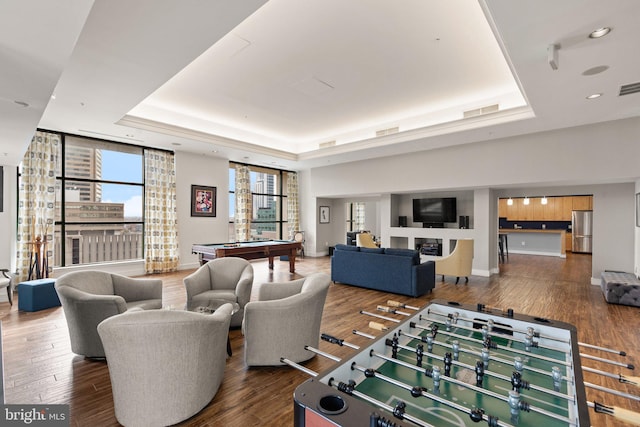 living room featuring billiards, hardwood / wood-style floors, a healthy amount of sunlight, and a raised ceiling