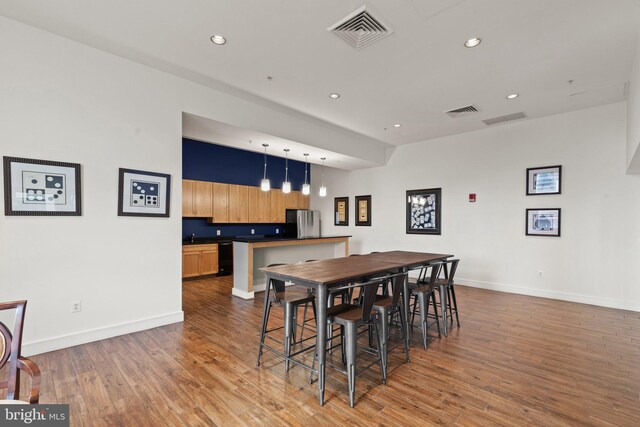 dining room with wet bar, wood finished floors, baseboards, and recessed lighting