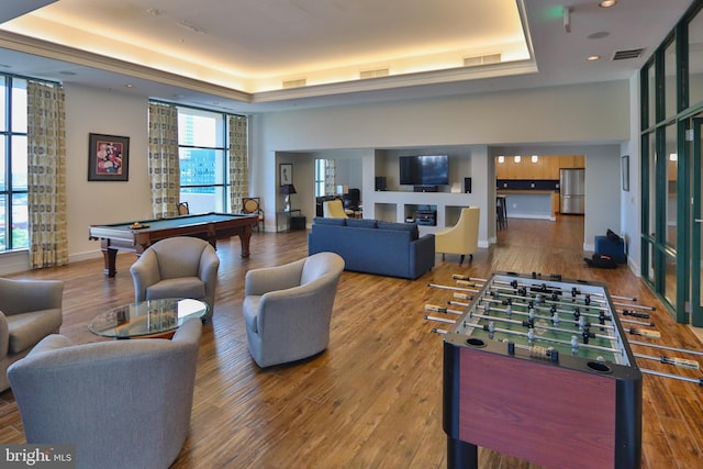 rec room with pool table, wood-type flooring, and a tray ceiling