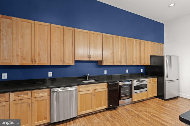 kitchen with stainless steel appliances, sink, light brown cabinets, beverage cooler, and light hardwood / wood-style flooring