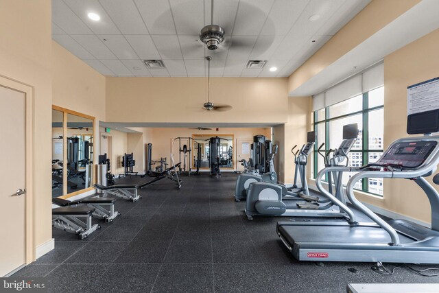 workout area featuring ceiling fan, a high ceiling, a paneled ceiling, and recessed lighting