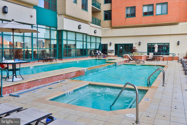 indoor community pool with an in-ground hot tub and a patio area