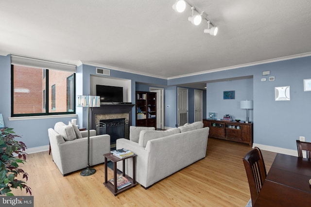 living area featuring light wood-style flooring, a fireplace, baseboards, ornamental molding, and track lighting