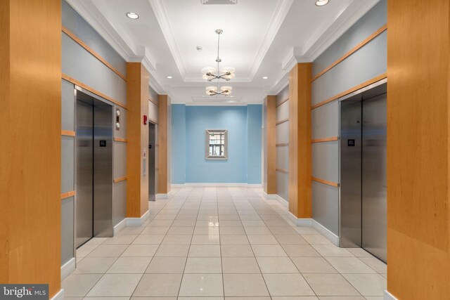 corridor featuring a chandelier, elevator, a raised ceiling, crown molding, and tile patterned floors