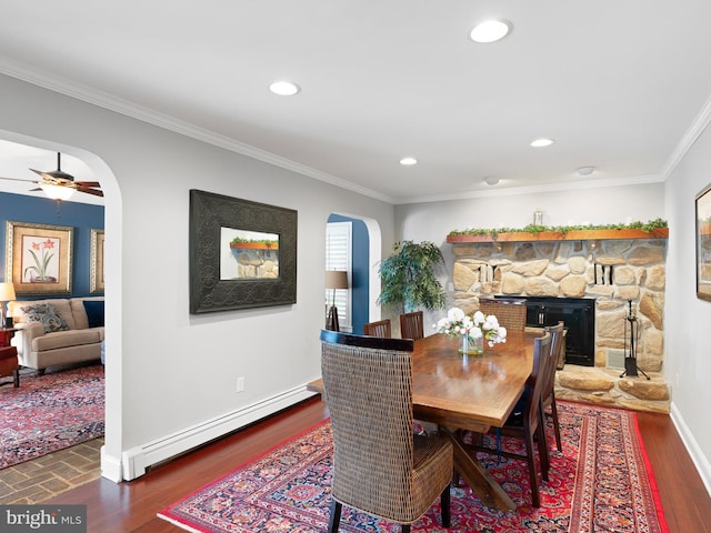 dining area featuring a baseboard radiator, a fireplace, ceiling fan, ornamental molding, and dark hardwood / wood-style floors