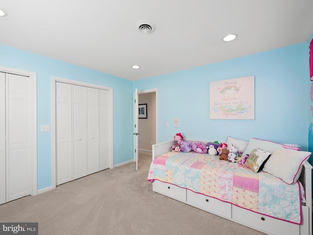 bedroom featuring light carpet and two closets