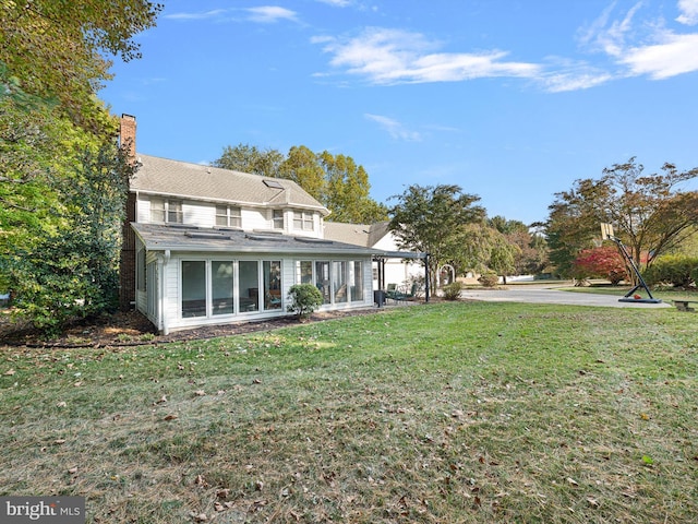 back of house featuring a lawn and a sunroom