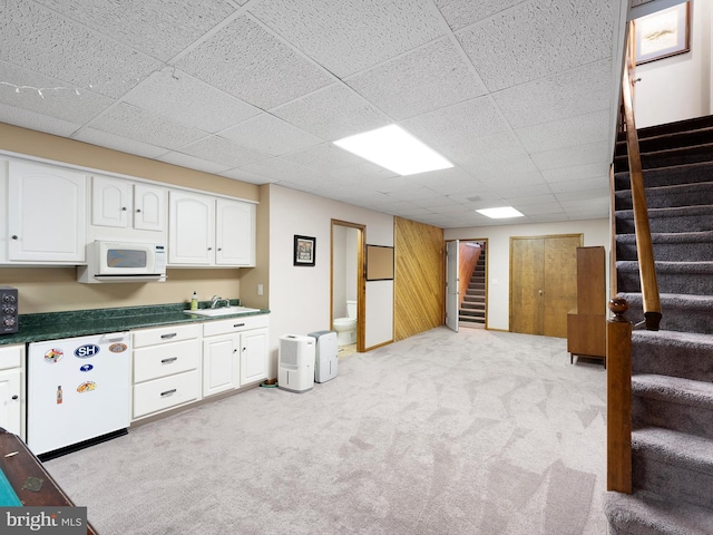 basement with white fridge, light carpet, sink, and a drop ceiling