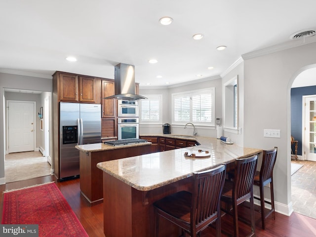 kitchen with appliances with stainless steel finishes, dark hardwood / wood-style flooring, kitchen peninsula, and island range hood